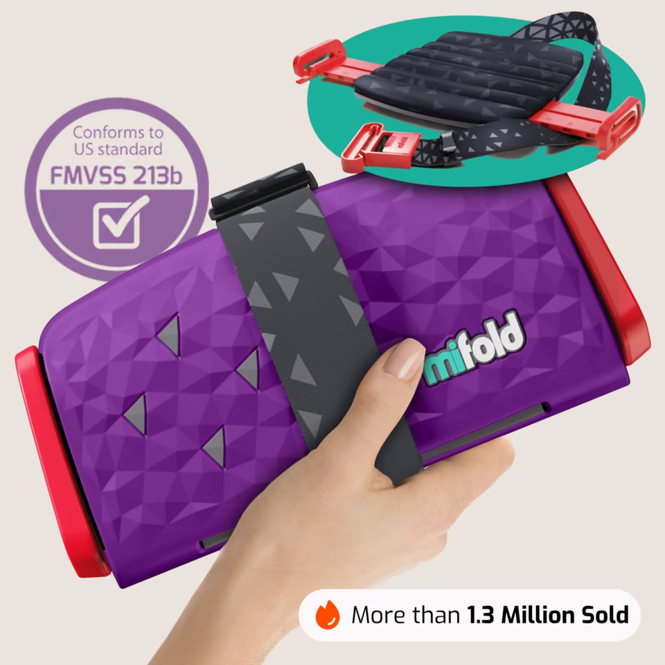 Mifold Comfort in Royal Purple: folded booster held in one hand with its FMVSS 213b safety badge and 1.3 million sold proof